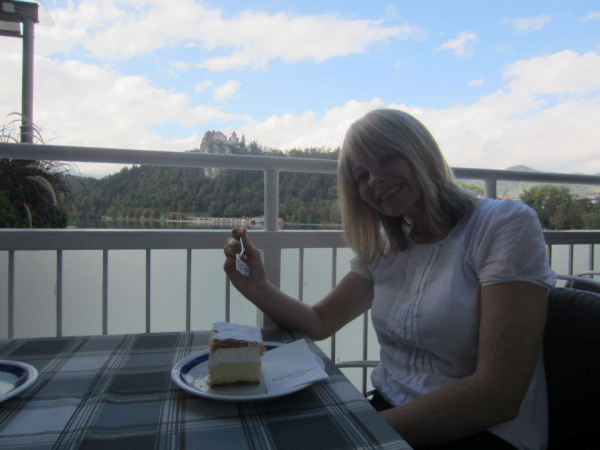 Kat munching a kremsnita with Bled castle in the background